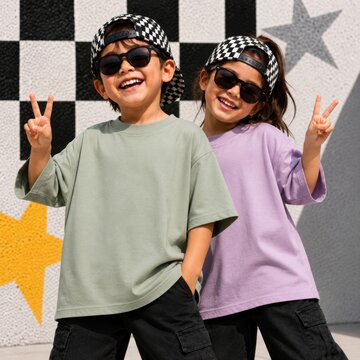Girl and boy in sunglasses and caps posing by wall. Kids short sleeve tee template. Olive and lilac oversized shirt design for friends, siblings, cousins. Children t-shirt mockup, summer outdoors