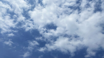 Fototapeta premium Patchy white clouds scattered across deep blue sky