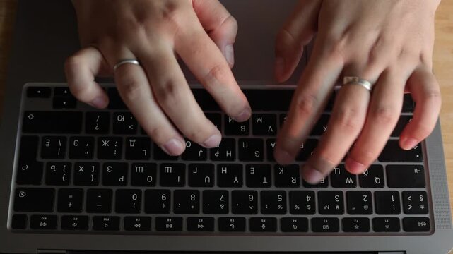 Close-up of hands typing on a laptop keyboard with Cyrillic letters