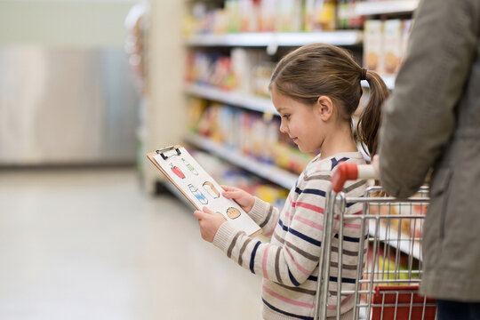 Child Using Grocery Shopping Visual Schedule Cards In Supermarket