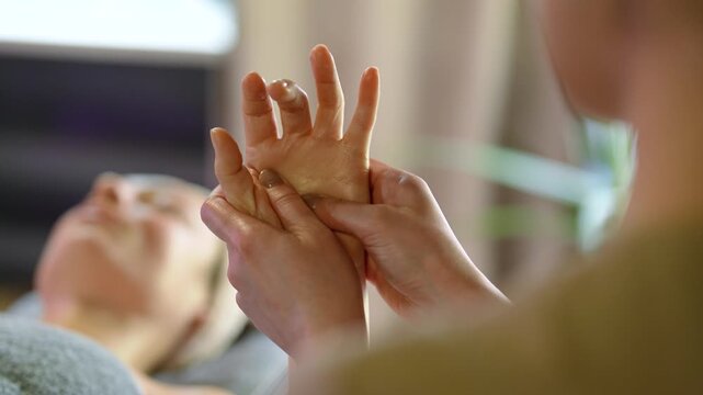 Close up of professional therapist performing relaxing hand, palm massage with aromatic oil in spa setting. Gentle manual treatment for relieve tension, improve circulation and promote relaxation.