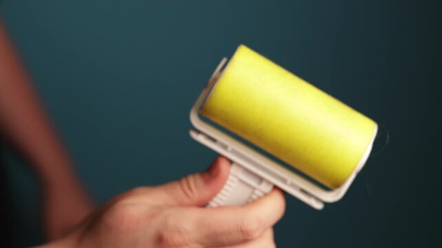 Close-up of a person using a sticky lint roller for cleaning clothes