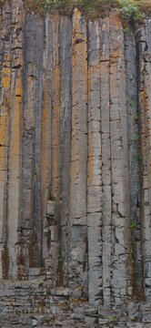 Towering basalt rock columns with golden lichen in Iceland