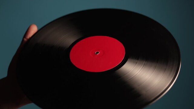 Close-up of a hand holding a vintage vinyl record with a red label