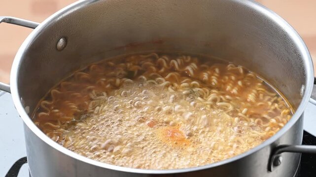 Close up of spicy instant noodles soup boiling in a pot