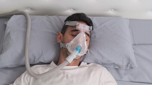 Man sleeping with CPAP mask for sleep apnea treatment in bed