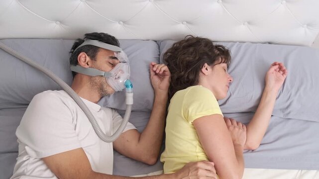 Couple sleeping in bed with CPAP therapy for sleep apnea