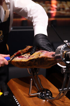 profesional limpiando un jam&oacute;n ib&eacute;rico de tocino y la capa que lo cubre
