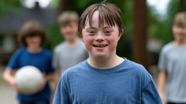 Boy with Down syndrome smiles while playing soccer outdoors with friends in a park, surrounded by trees and grass, showcasing a joyful moment of childhood