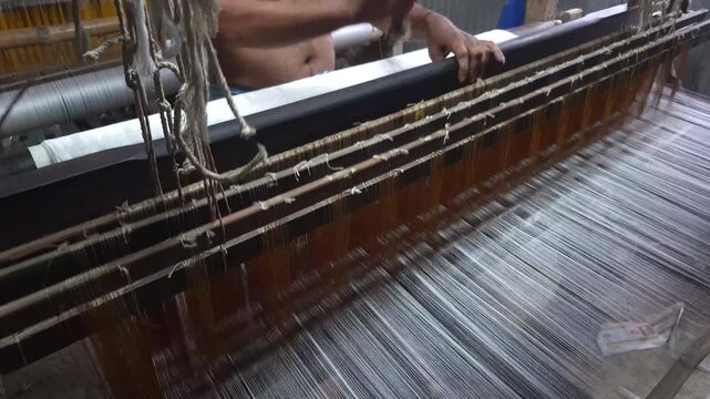 4k 120 fps slow motion video of a handloom weaver in India working in his loom.	