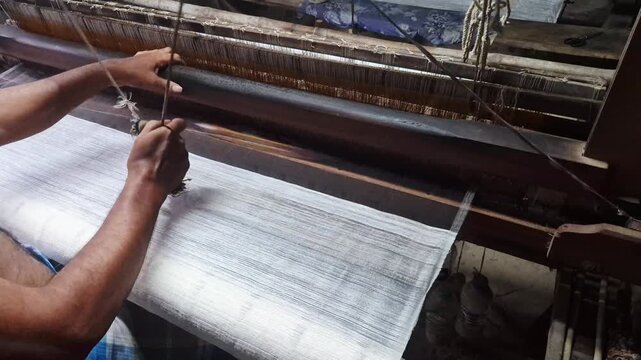 4k 120 fps slow motion video of a handloom weaver in India working in his loom.	