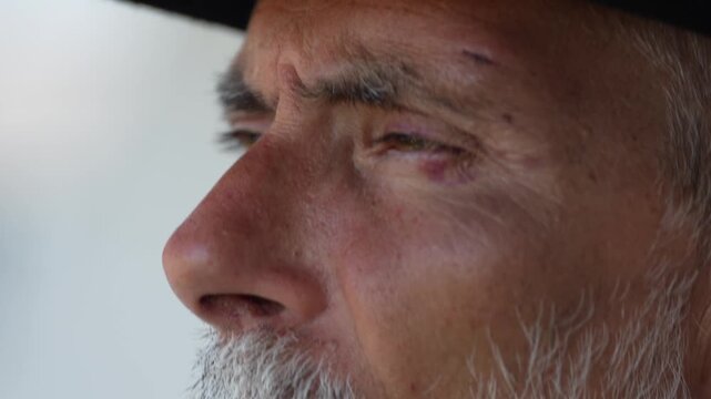 Cinematic 4K close up of a tough silver fox with a black eye, looking directly into the lens. For luxury ads, movie posters and brutal fashion