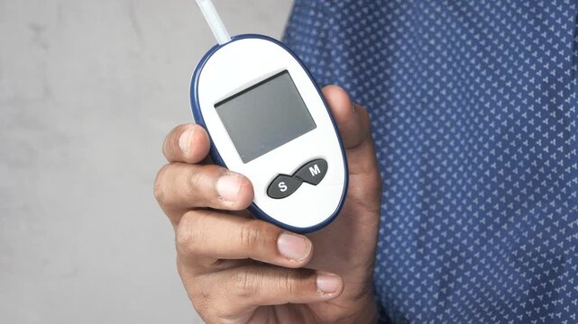 Close up shot of man holding glucometer machine checking sugar level showing important healthcare technology dynamic clip