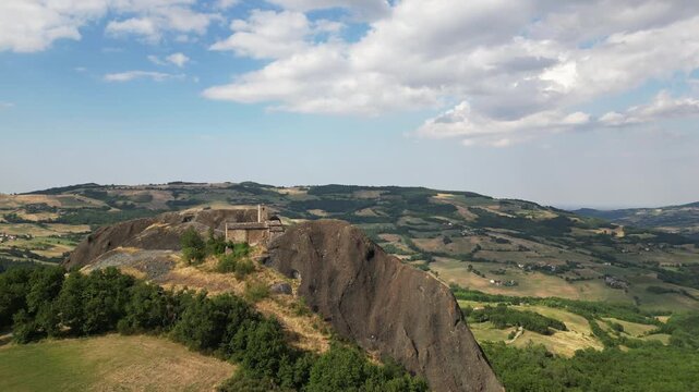 Italy, Travo , Drone aerial view Pietra Perduca is a  volcanic rock, the  church  in stone immersed in a  countryside Apennines landscape with cultivated land in Val Trebbia Bobbio Emilia Romagna