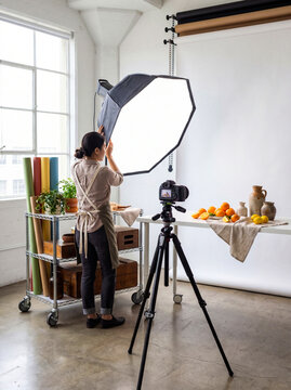 Professional photographer setting up studio lighting. Food stylist preparing a photoshoot.