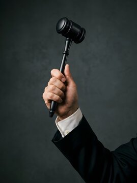 Judge hand holding a wooden gavel ready to strike in a courtroom
