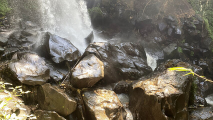 Rushing waterfall water over dark wet volcanic rocks © Manda Art