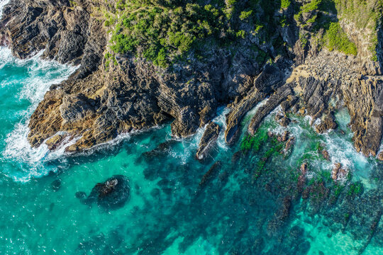 Aerial view of the rugged rocky coastline and crystal-clear turquoise water along the shoreline at Seal Rocks, NSW, Australia, showcasing the natural beauty of this iconic coastal destination.