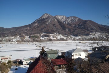 雪に包まれた山岳地帯と冬の集落を捉えた静かな風景   Serene winter landscape featuring snow‑covered mountains and a valley village  © 拓也 山並