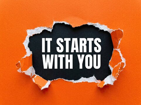 Orange paper torn open to reveal "IT STARTS WITH YOU" text, representing personal responsibility and motivation Concept, powerful message for self-empowerment and taking action.