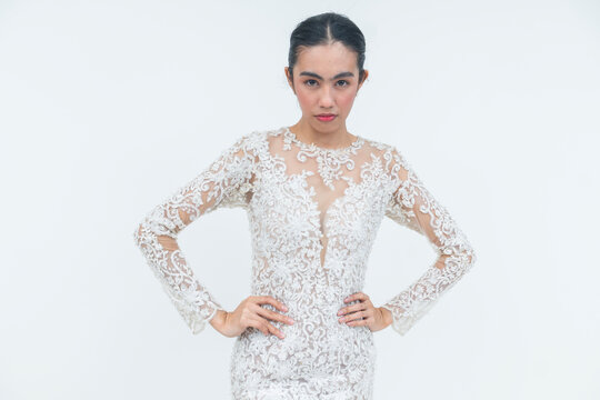 A young Filipino bride in an elegant lace wedding gown poses with hands on her waist, showing confidence and a serious expression.