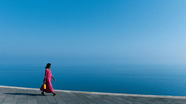 Woman in Pink Dress Walking by Serene Blue Ocean
