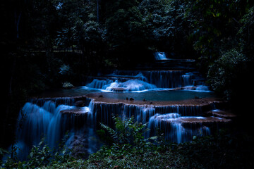 Fototapeta premium Long Exposure Cascades Softly Glow In The Dark Tropical Rainforest During Twilight At Huai Mae Khamin Waterfall In Kanchanaburi Thailand