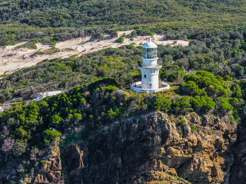 Aerial vertical view of the historic Seal Rocks Lighthouse overlooking the rugged coastline, deep blue ocean and surrounding coastal landscape at Seal Rocks, NSW, Australia.