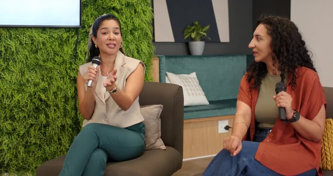 Female panel camera framing left speaker with mic in blazer gesturing discussing Lets Talk About AI