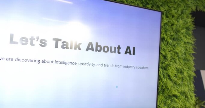 Two female speakers reacting to slide 'Let's Talk About AI', laughing with microphones in lounge