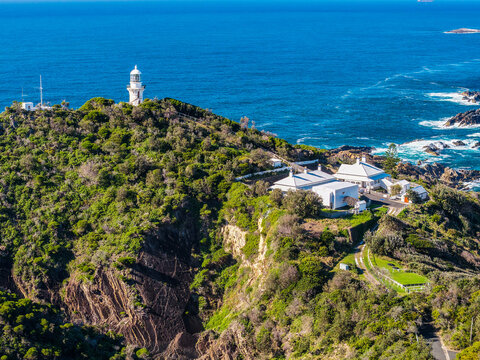 Aerial view of Lighthouse Beach leading towards the historic Seal Rocks Lighthouse, showcasing golden sand, rugged coastline and the clear blue waters of the Pacific Ocean at Seal Rocks, NSW