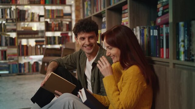 Happy red-haired woman and her boyfriend discussing a book in urban library