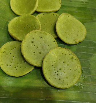 Fresh pandan serabi arranged on banana leaf. Authentic Indonesian rice pancakes featuring traditional texture and vibrant green color