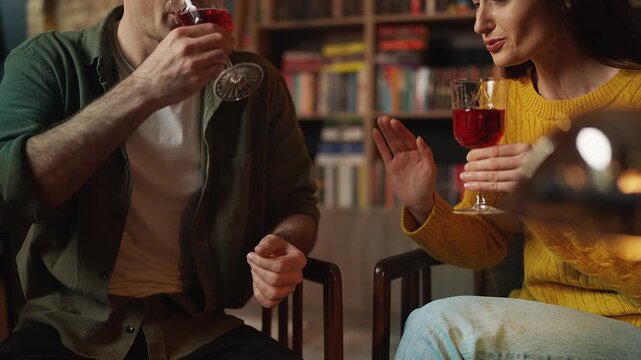 Young man and woman drinking wine and talking during date in coffee shop