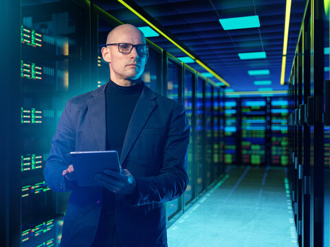 Data center operations. IT specialist monitors server infrastructure in data center using tablet for network management and system administration.