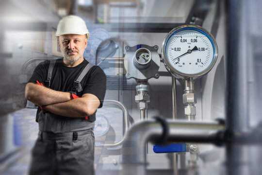 Industrial maintenance. Maintenance engineer stands near pressure gauges and process equipment at industrial plant during inspection and monitoring.