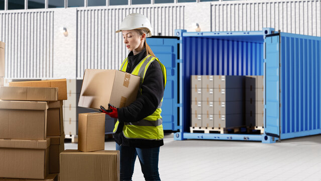 Warehouse logistics. Female warehouse worker handles cardboard boxes near shipping container during cargo loading and order fulfillment operations.