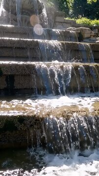 Cascading Water Over Stepped Concrete Fountain - A close-up view of water gracefully cascading down a series of stepped concrete levels in an outdoor fountain.