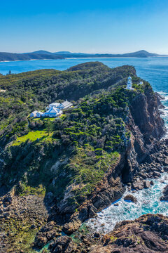 Aerial vertical view of the historic Seal Rocks Lighthouse overlooking the rugged coastline, deep blue ocean and surrounding coastal landscape at Seal Rocks, NSW, Australia.