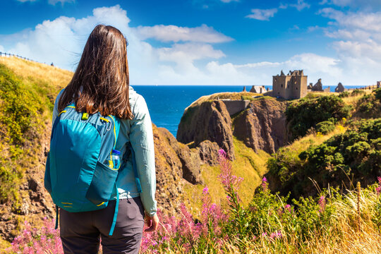 Female hiker at Dunnottar Castle ruins on sea cliffs near Stonehaven, Aberdeenshire, Scotland, UK