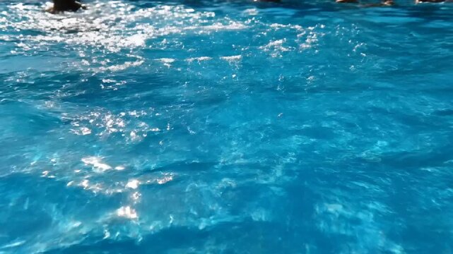 Clear blue water surface with sunlight reflections and ripples