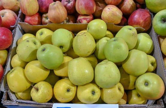 Fresh green and red apples on display for sale at an open-air market. Variety of apples stacked in crates at a local farmer's market. Red and green organic apples.