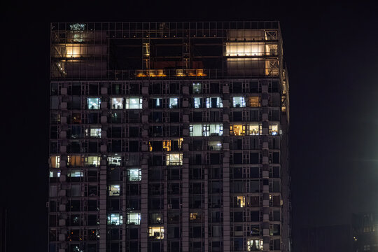 modern high-rise residential skyscrapers featuring vertical light strips and numerous lit apartment windows at night