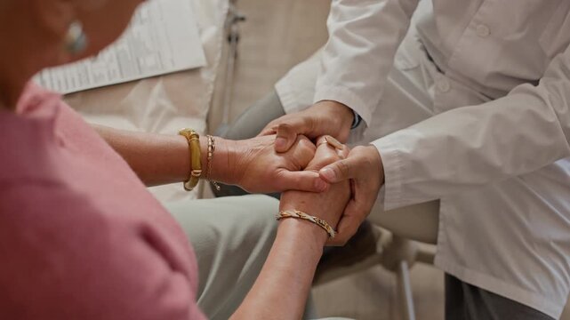 Caucasian male doctor holding hands of Caucasian senior woman in comforting gesture after writing on clipboard. Footage is ideal for senior care and medical empathy campaigns