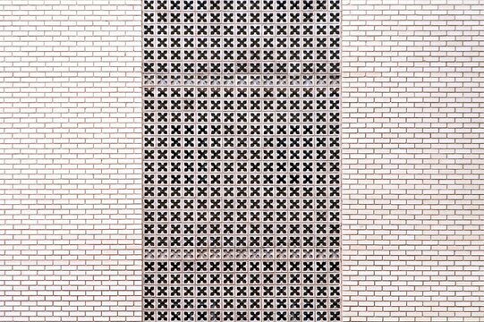 Centered flower shaped breeze block ventilation wall pattern flanked by white brickwork background, architectural geometric facade and symmetry concept