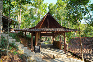Obraz premium Traditional Javanese wooden gazebo surrounded by lush green forest.