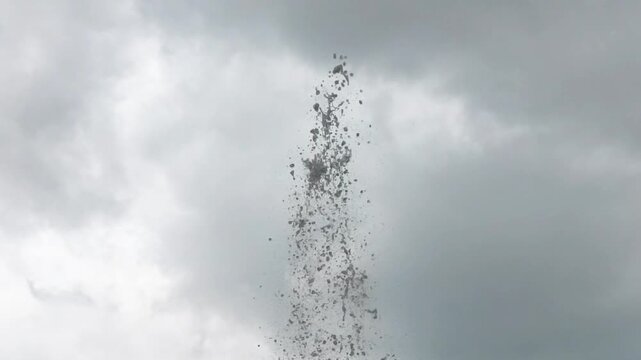 Dynamic water splash erupting vertically against a moody overcast grey sky background for conceptual design