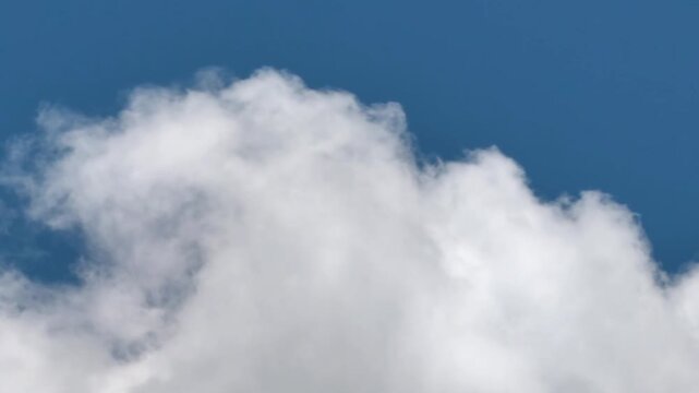 Fluffy white clouds against a vibrant bright blue sky on a sunny summer day nature background