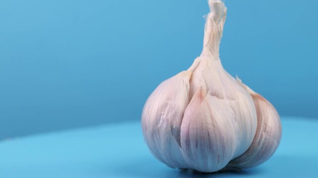 Close-up macro footage of a fresh garlic bulb rotating slowly, showing its natural texture and layered cloves.