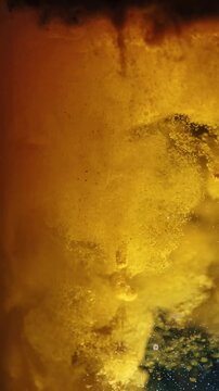 Macro shot of yellow liquid mixing with particles in close up abstract background